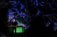 a man in a suit standing in front of a green screen