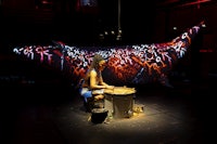 a woman is playing a drum in a dark room