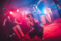 a woman performs on stage in front of a group of musicians