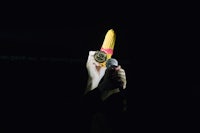 a person holding up a corn cob in the dark
